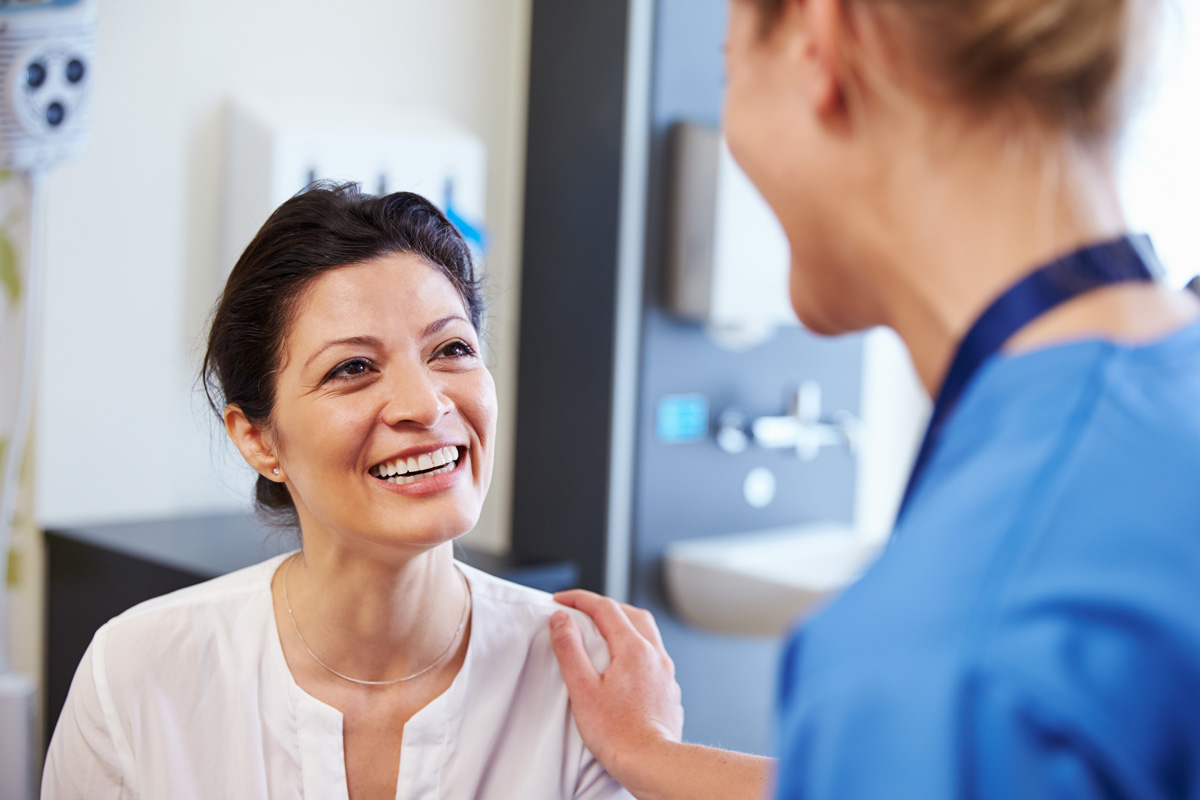 A smiling woman speaking to a healthcare worker in a walk-in clinic in El Paso.